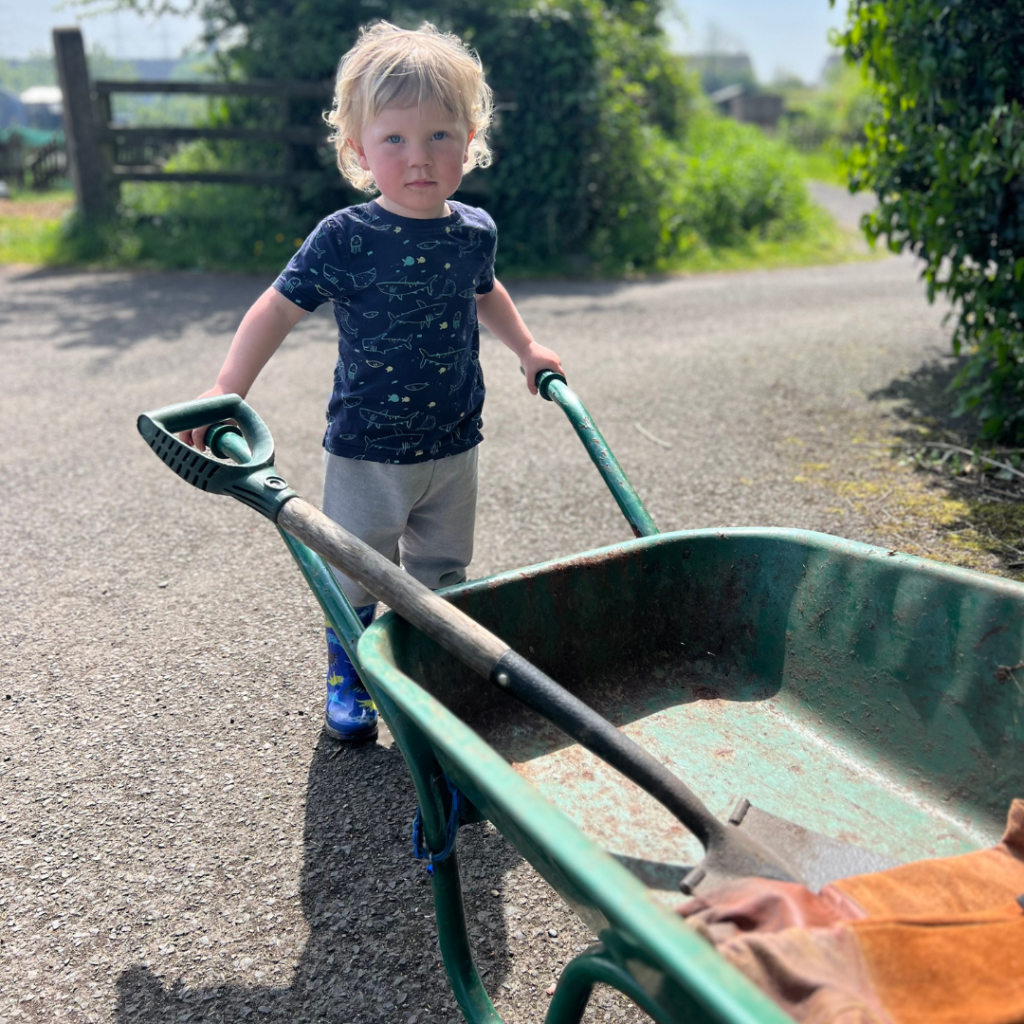Small boy holding a wheelbarrow
